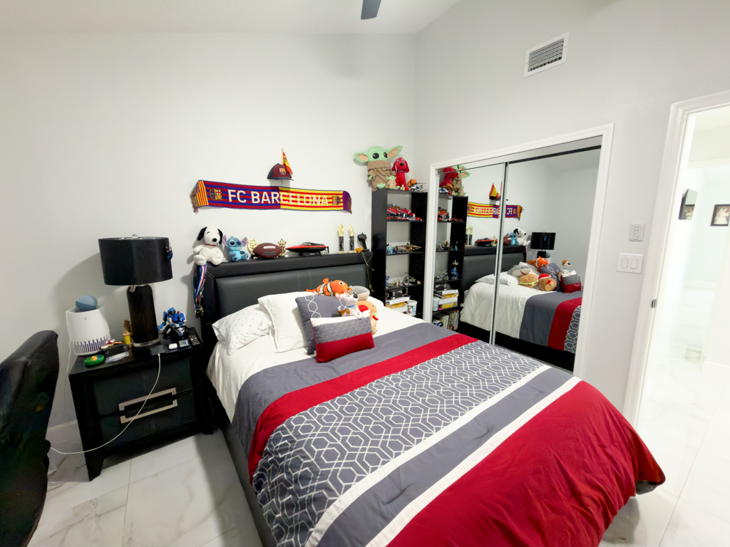 Bedroom with dark bed frame, FC Barcelona scarf and mirrored closet