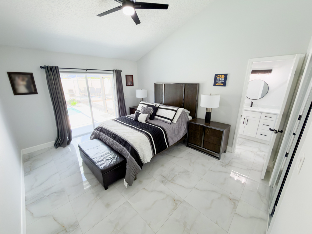 Primary bedroom with dark wood furniture and sliding doors to pool