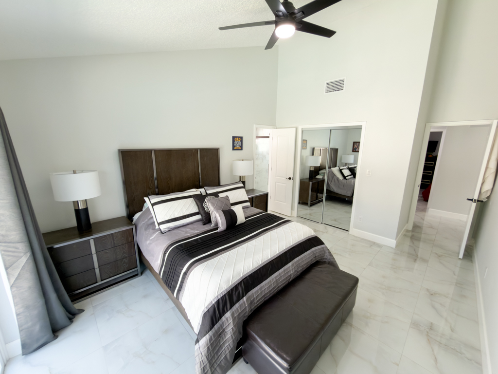 Primary bedroom with dark wood bed frame and mirrored closet doors