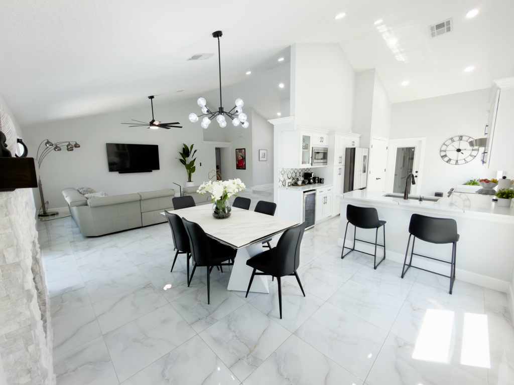 Open-plan dining room and kitchen with marble table, black bar stools and kitchen island