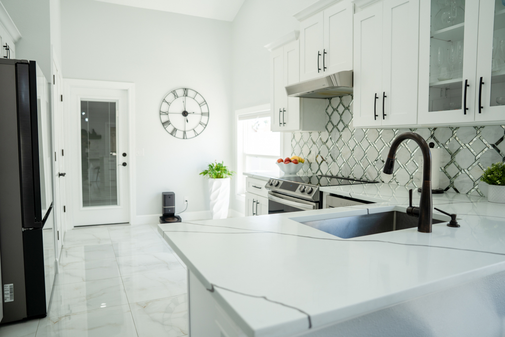 Kitchen with white quartz island, undermount sink and mirror-tile backsplash