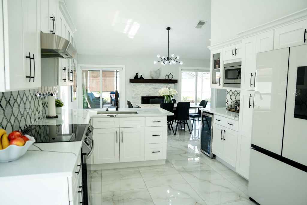 Full kitchen view with white cabinets, large island, stainless appliances and view to dining room