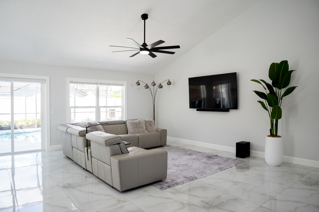 Living room with sectional sofa, TV and sliding doors to pool