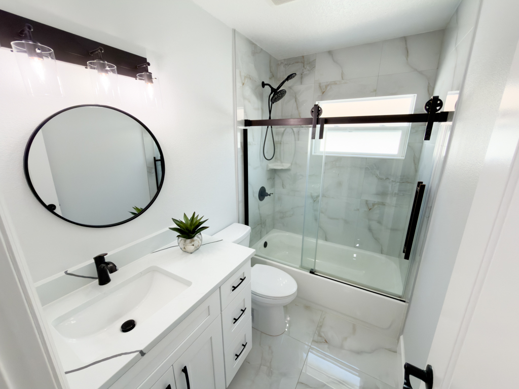Bathroom with single vanity, round mirror and glass sliding shower