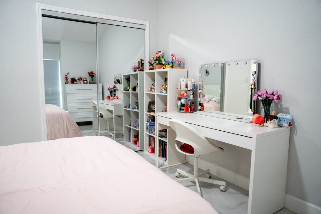 Bedroom with white vanity desk, shelving and mirrored closet
