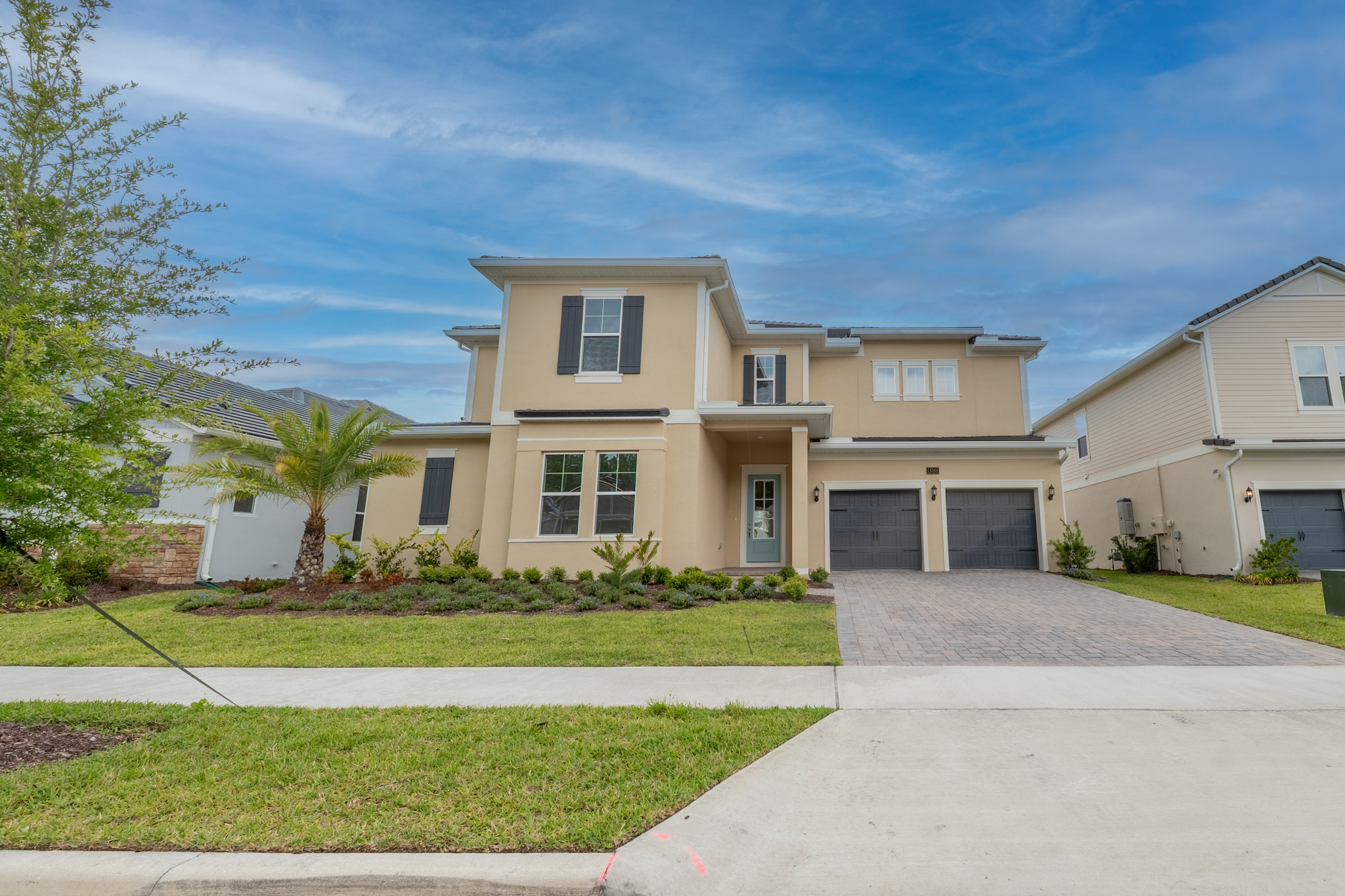 Front exterior of two-story single family home in Windermere, FL with palm tree and paver driveway