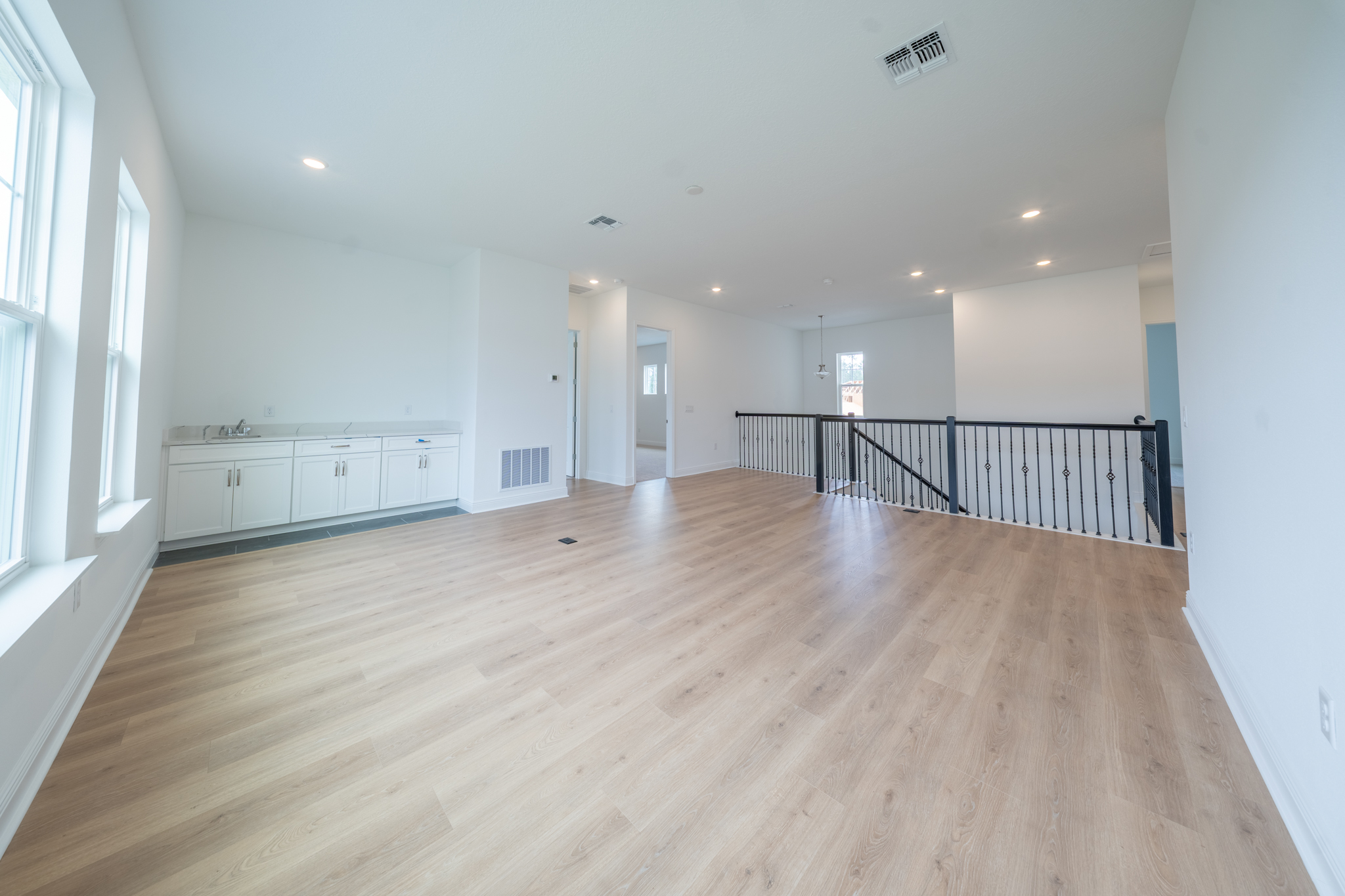 Second-floor loft with wet bar cabinetry and view toward upstairs bedrooms