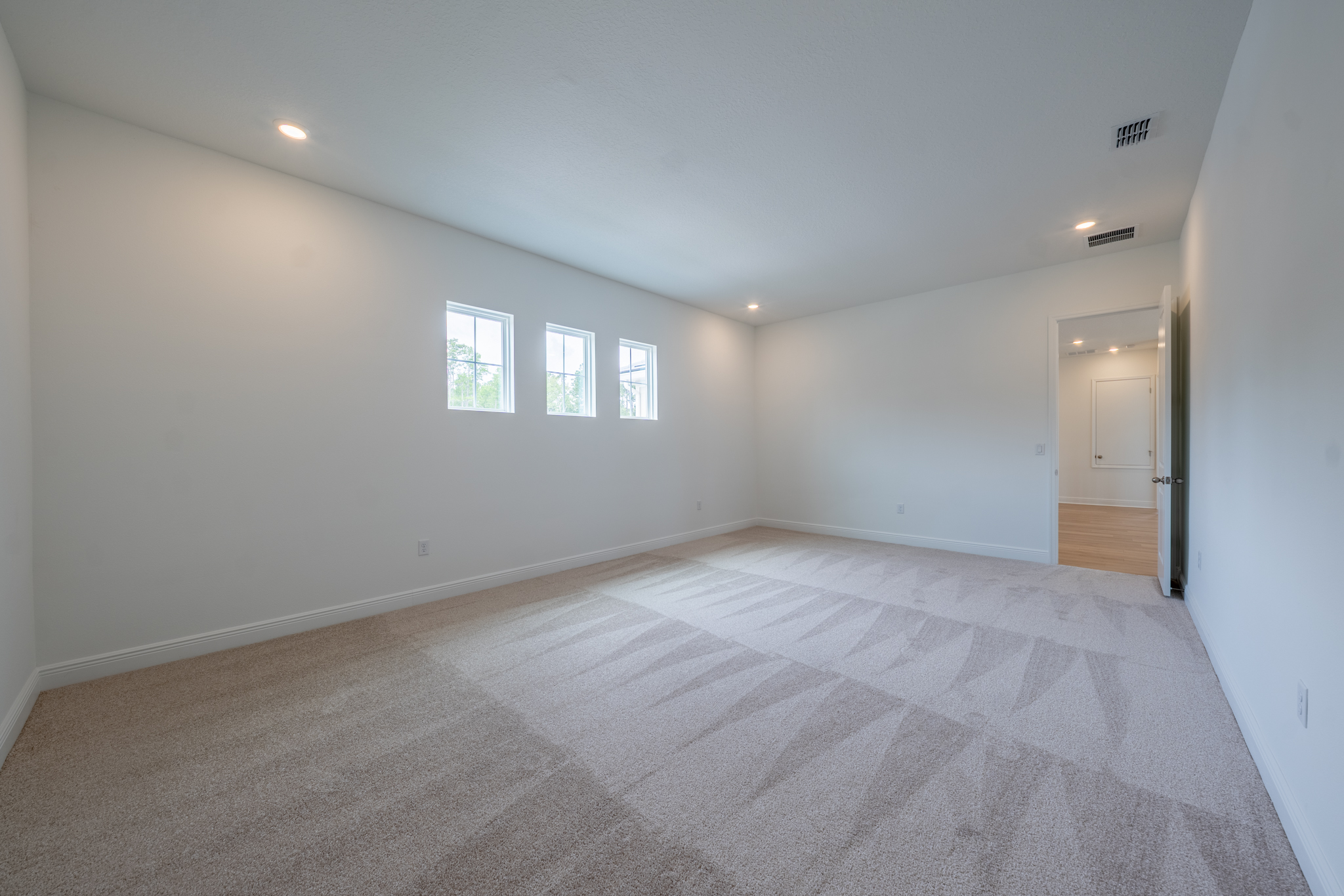 Empty bonus room with carpet, clerestory windows and door to hallway
