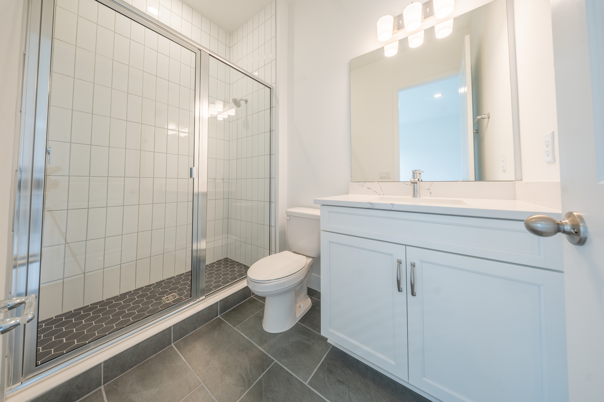 Bathroom with single vanity, glass shower enclosure and dark slate tile floor