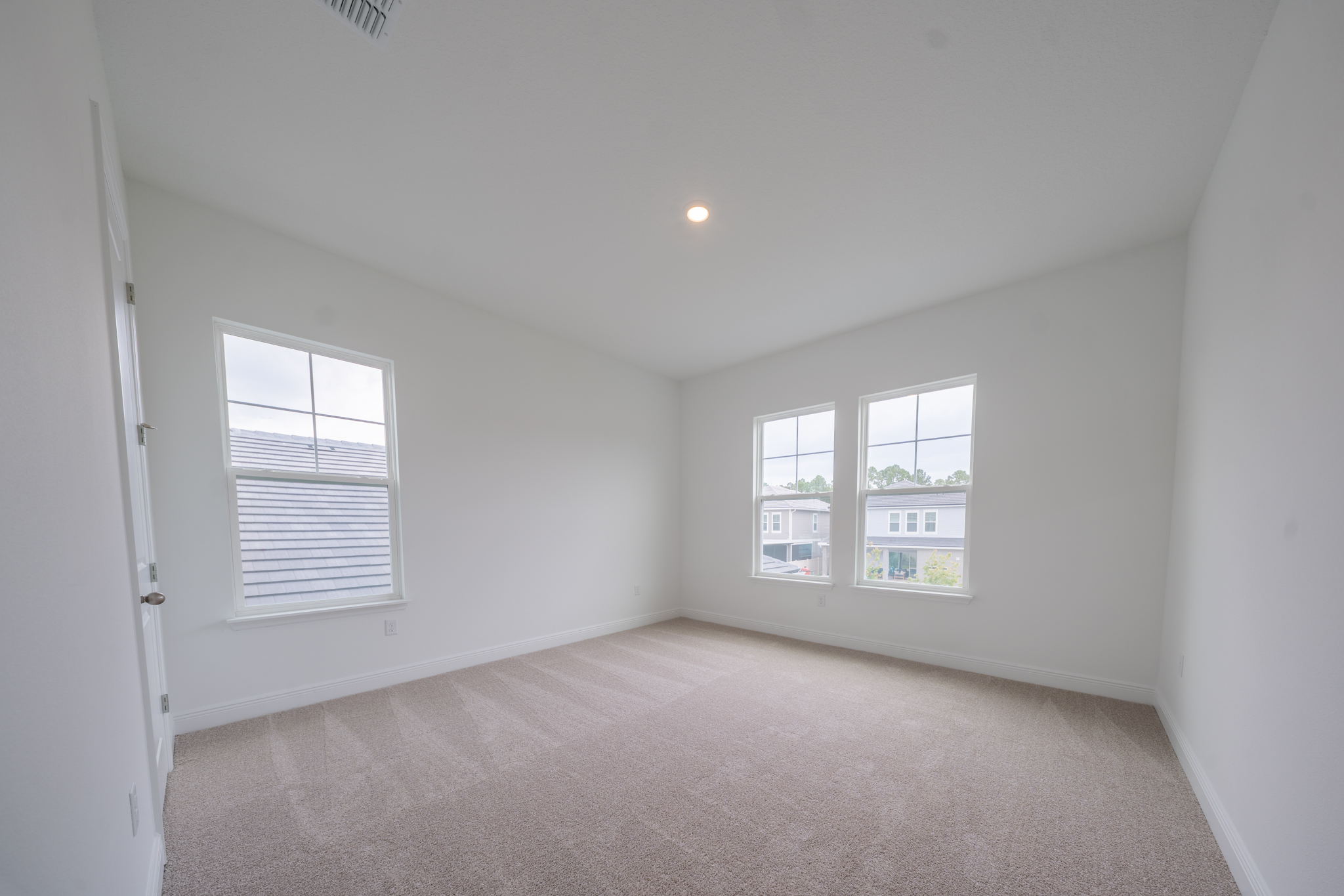 Empty carpeted bedroom with two windows and natural light