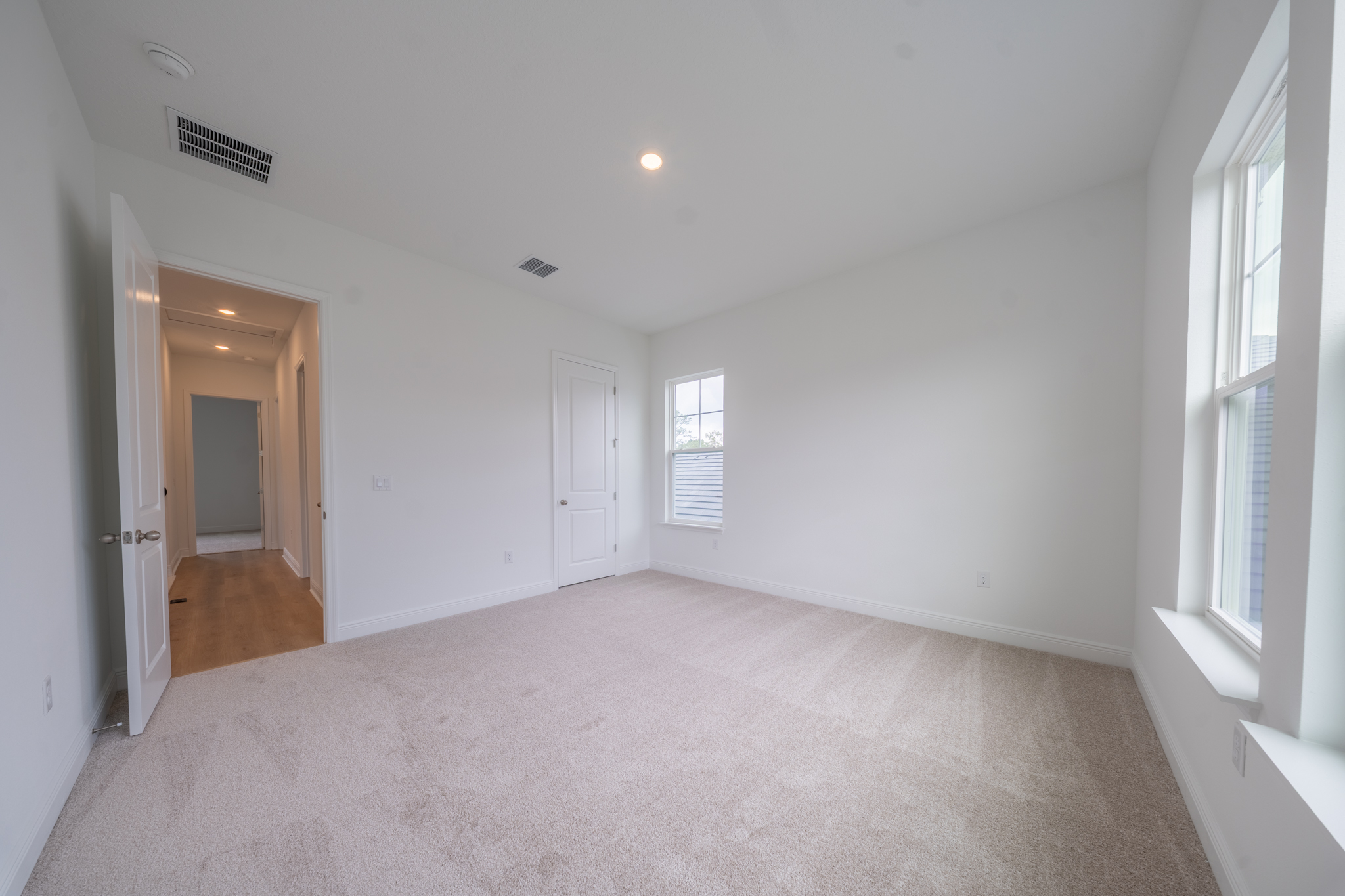 Empty carpeted bedroom with window and closet door