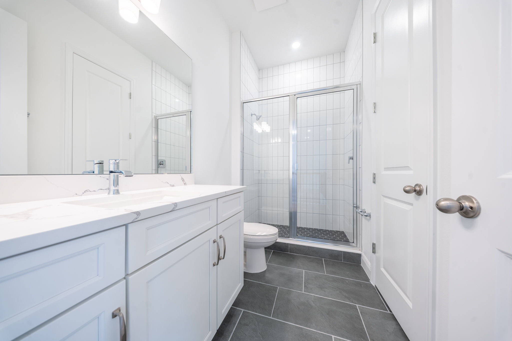 Bathroom with double vanity, quartz countertop and glass shower enclosure