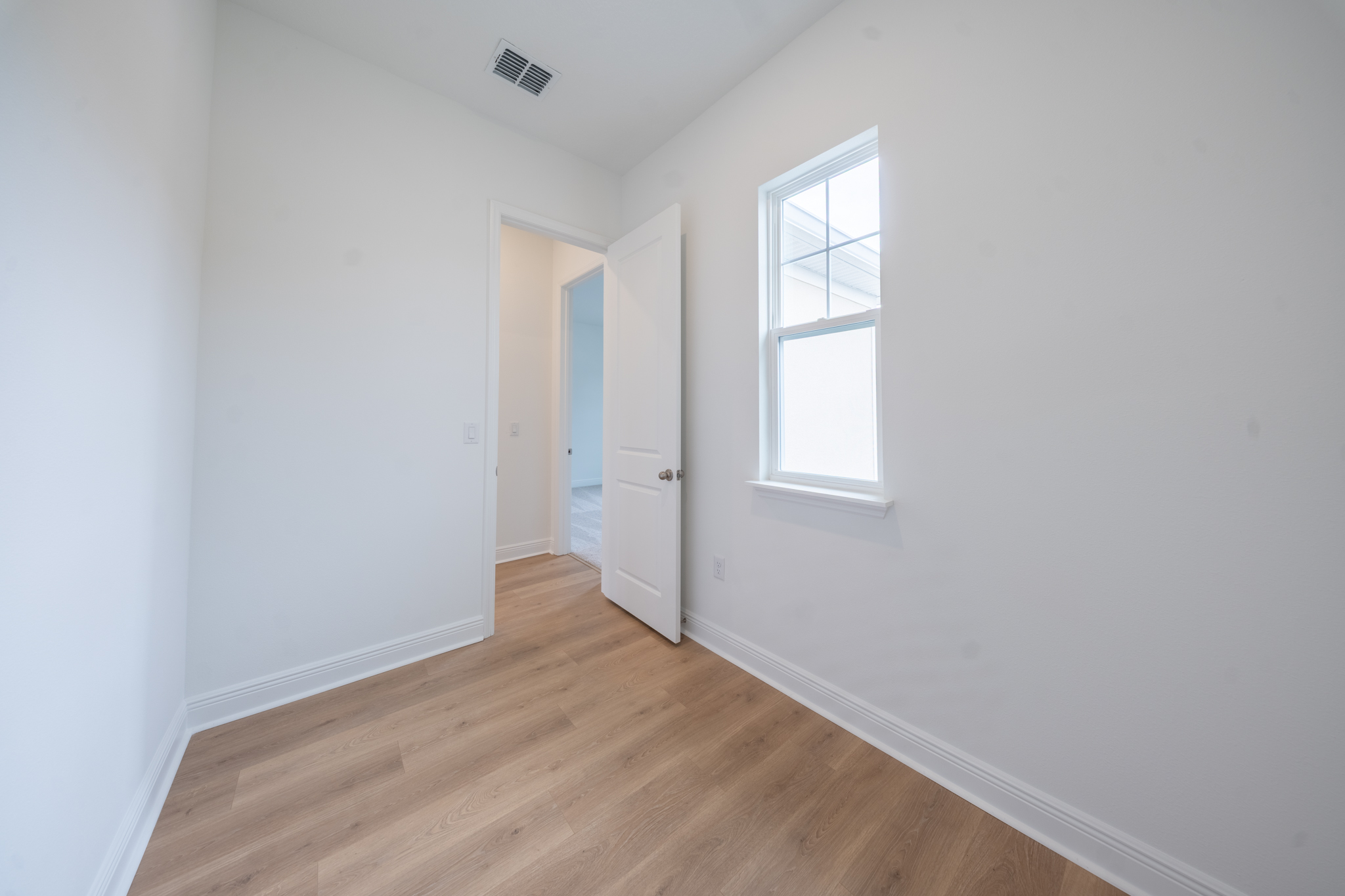 Small bedroom with hardwood floors and single window