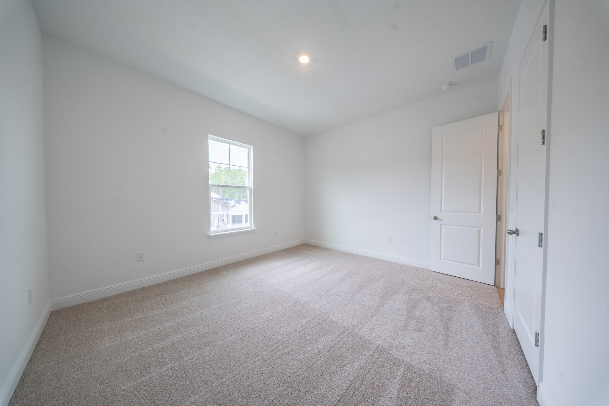 Carpeted bedroom with window and double-door closet