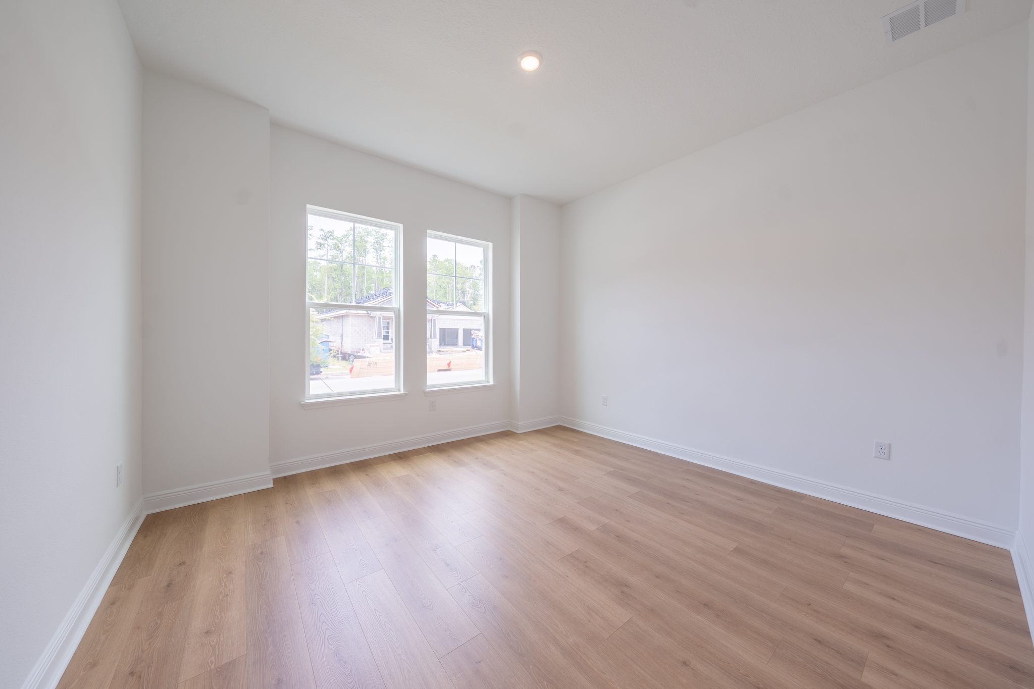 Empty flex room with two windows and light hardwood floors