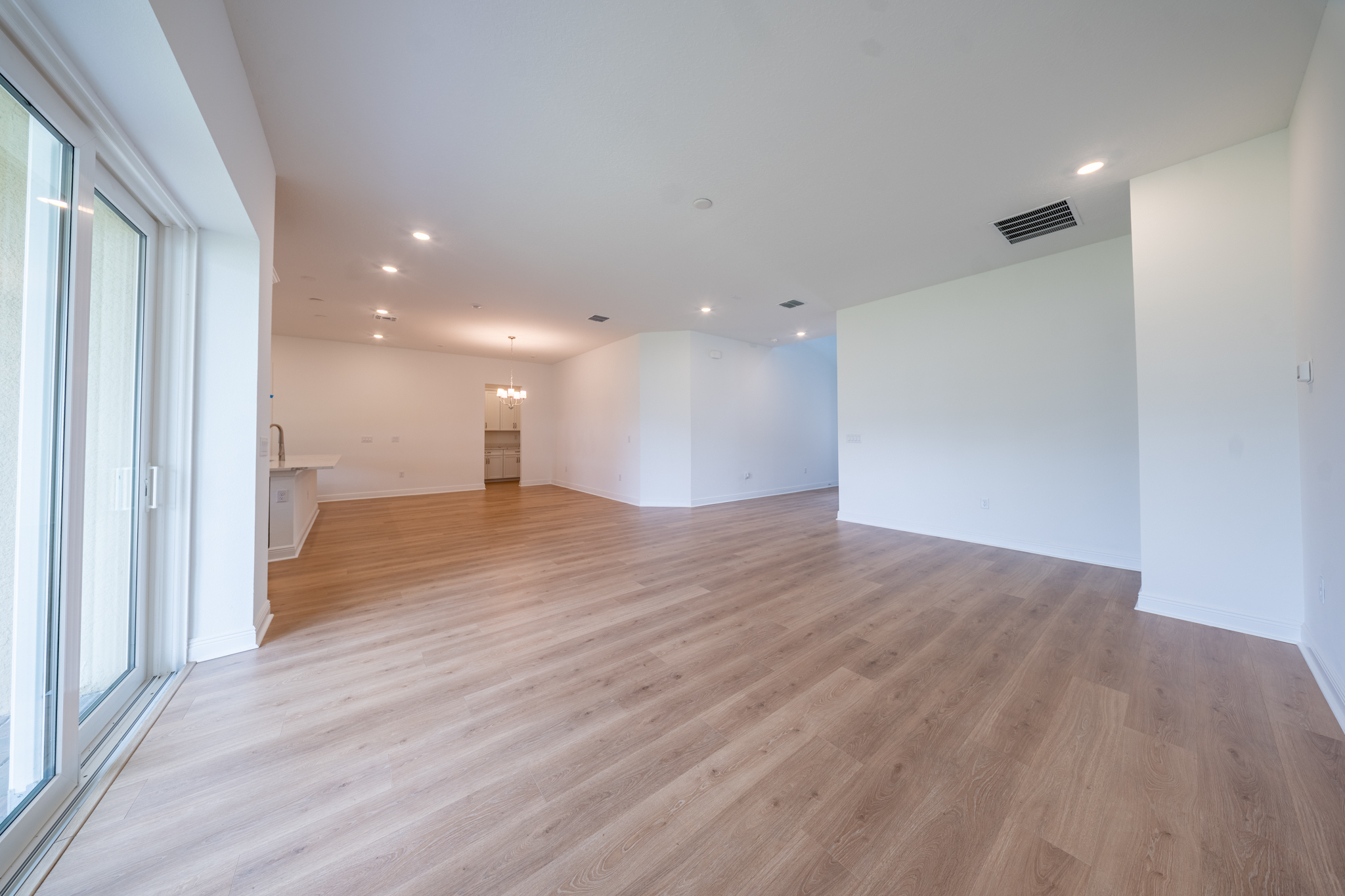 Open-plan living area viewed from sliding doors with kitchen island and dining space beyond