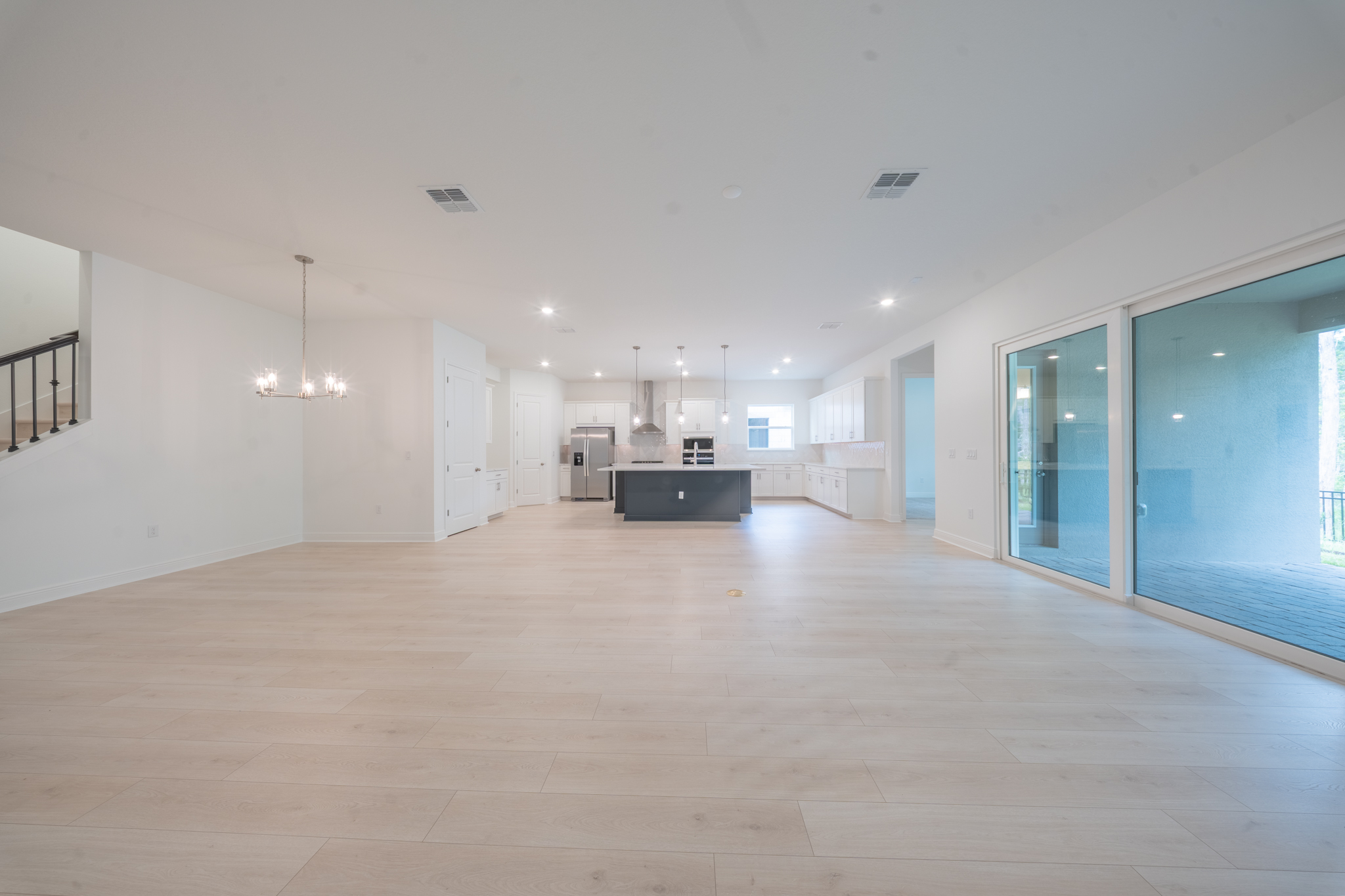 Wide open-plan living and dining area with staircase railing, navy island and sliding doors