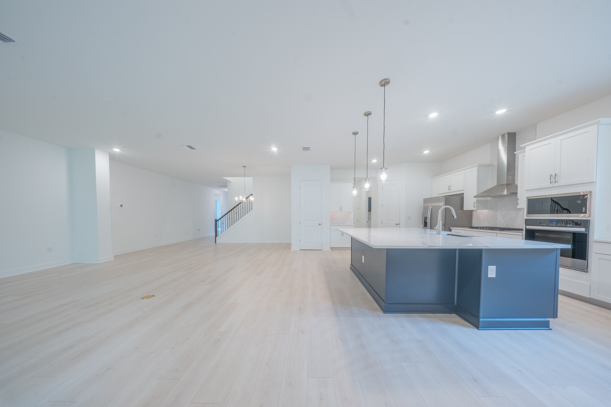 Kitchen with bold navy island, pendant lights, white upper cabinets and stainless appliances