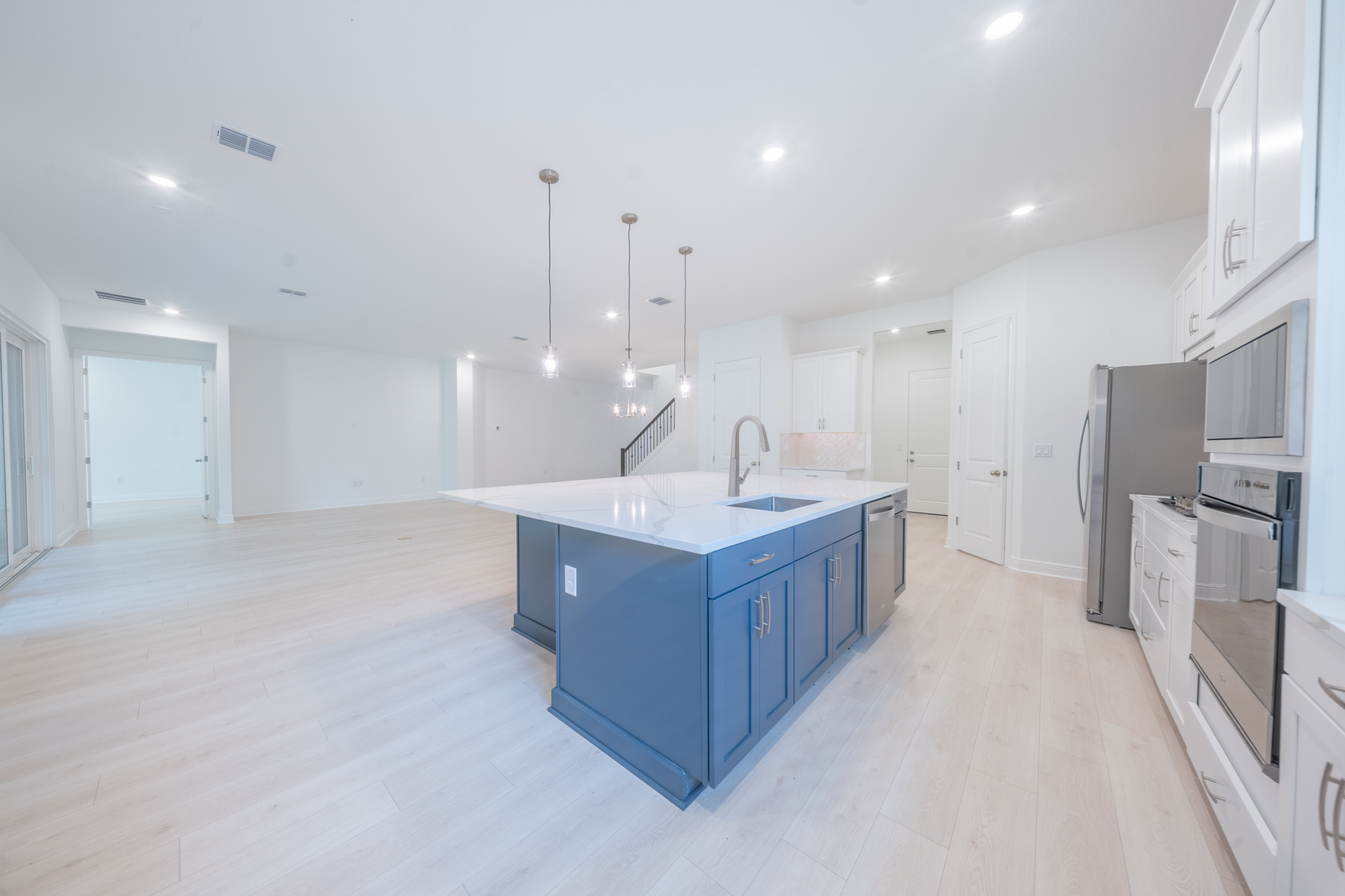 Kitchen with large navy island, quartz countertop, undermount sink and stainless refrigerator