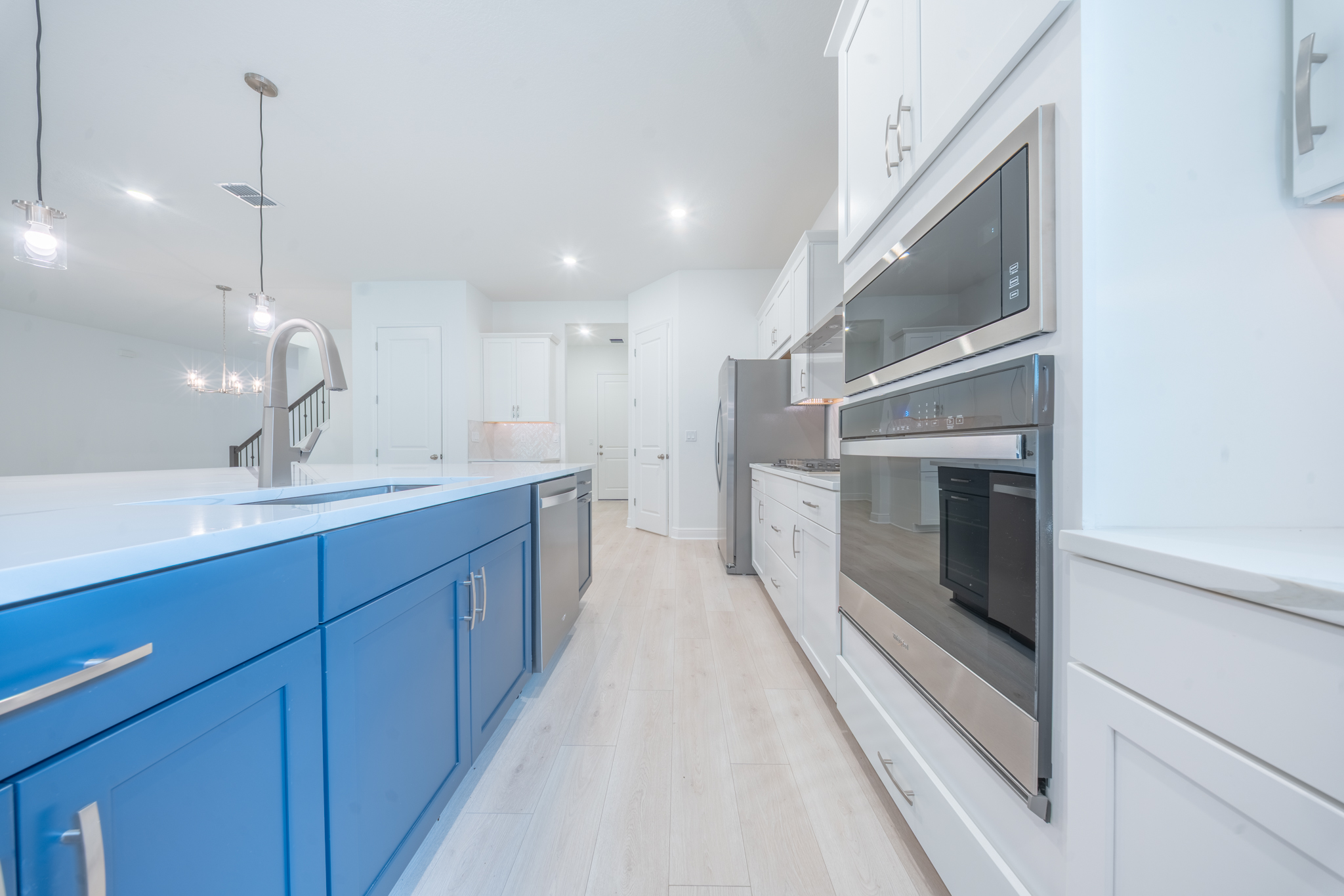 Kitchen detail with navy island, built-in double wall oven, microwave and stainless range