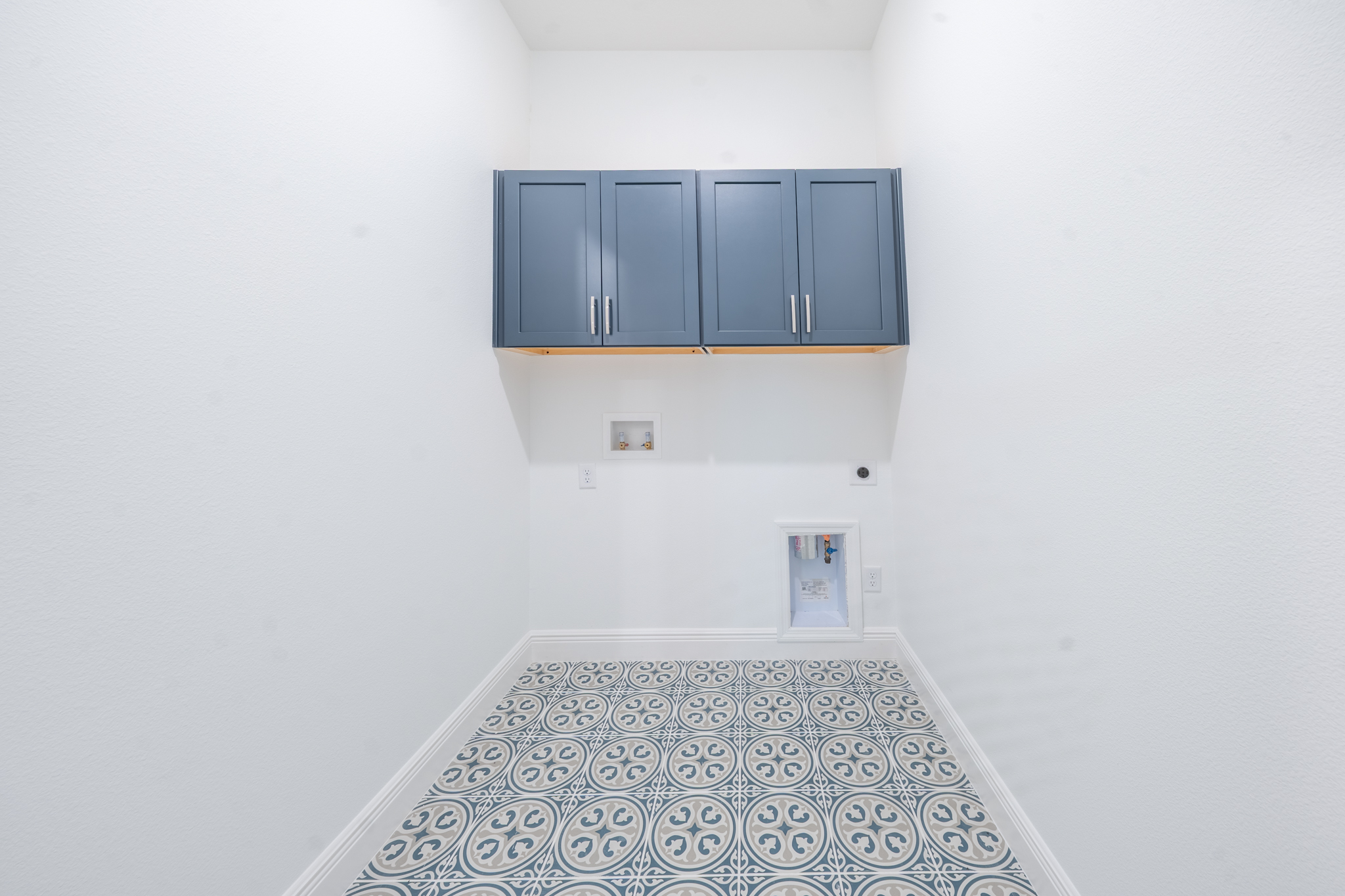Laundry room with navy upper cabinets and decorative patterned tile floor