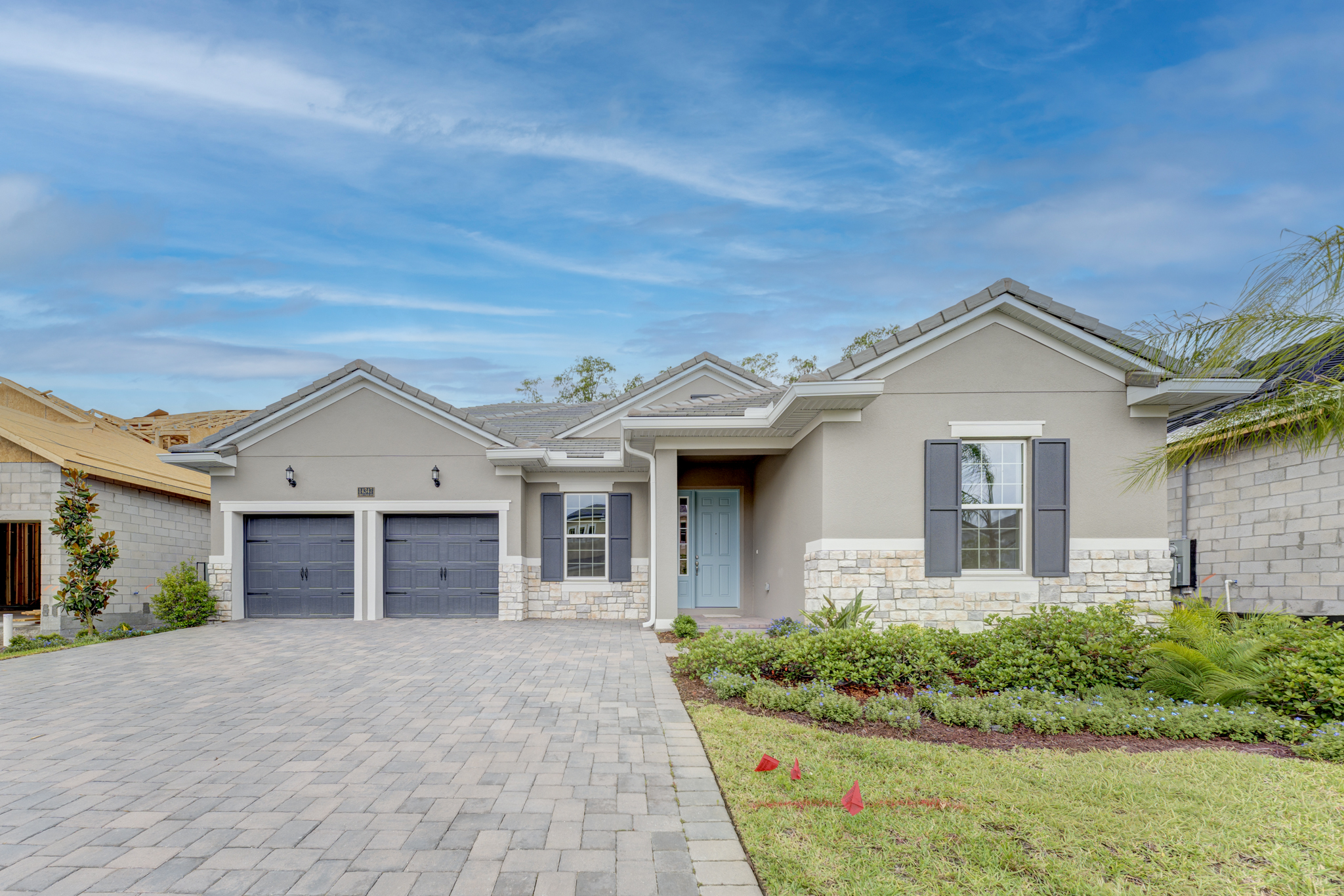 Front exterior of home with stone accent base, gray shutters and fresh landscaping