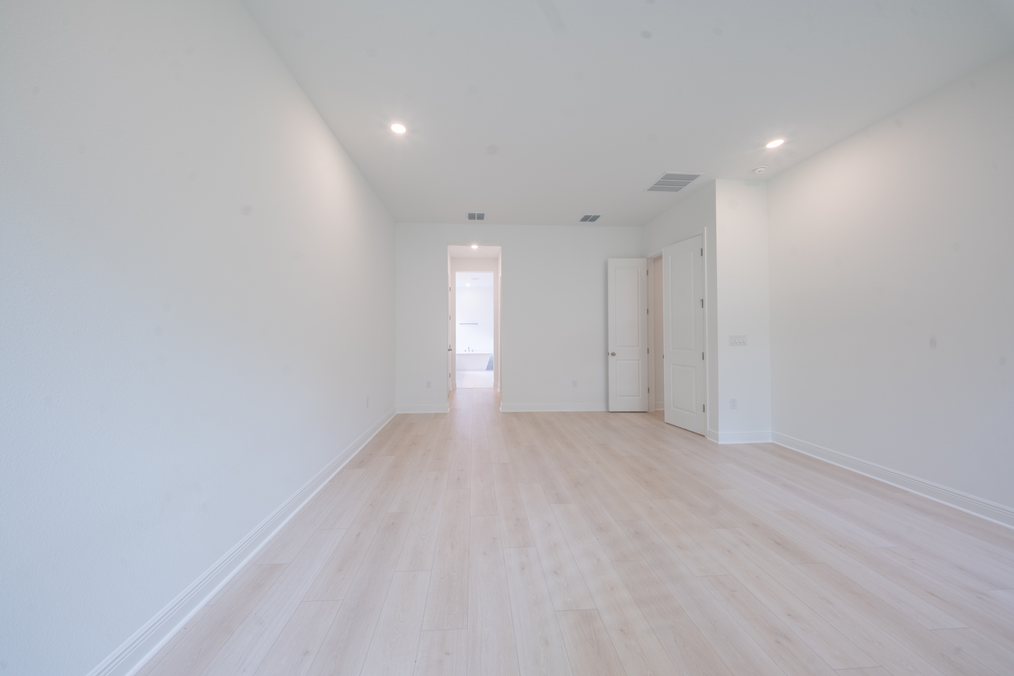 Primary bedroom sitting area with hardwood floors and door to en suite bathroom