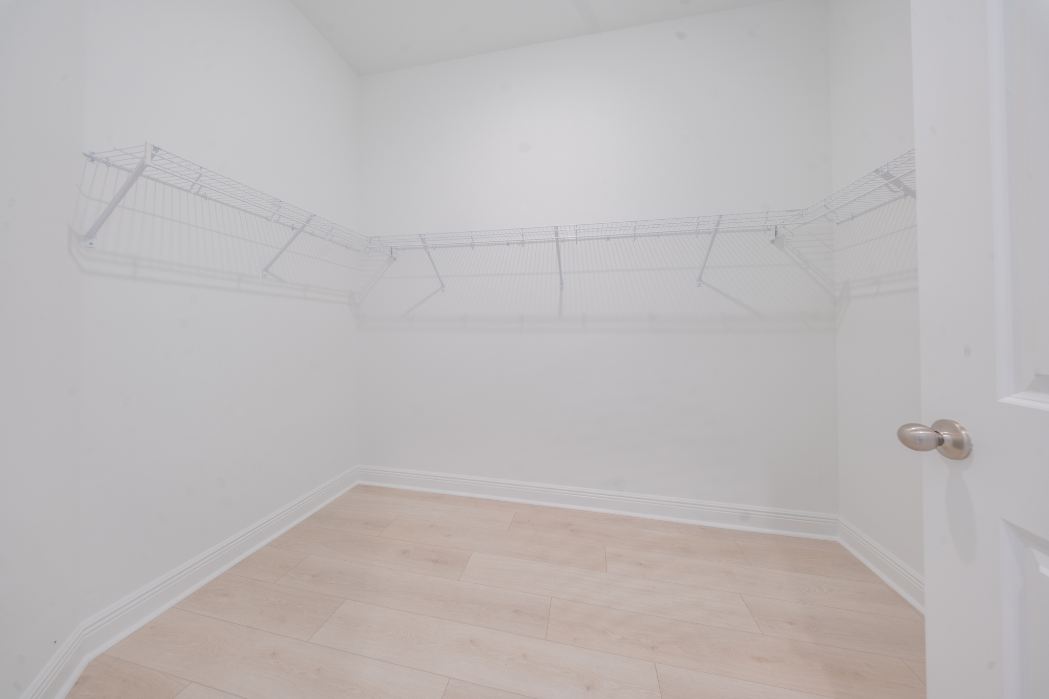 Walk-in closet with wire shelving and light hardwood floors