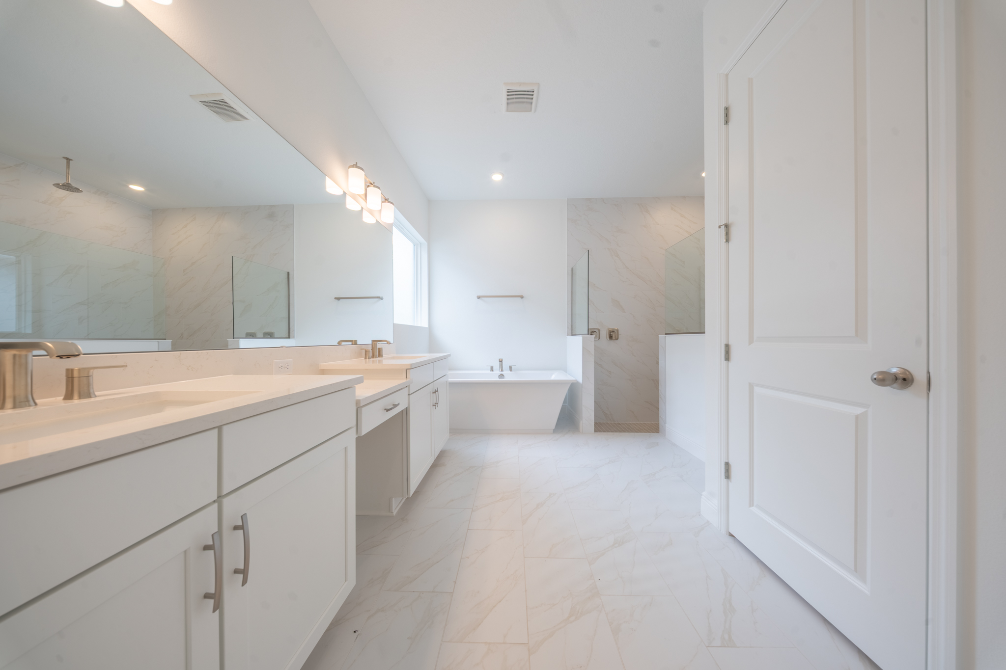 Primary bathroom with double vanity, freestanding soaking tub and frameless glass walk-in shower