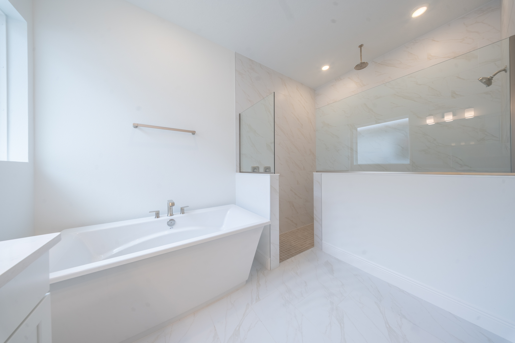 Primary bathroom detail with freestanding soaking tub and open frameless glass shower with rain head