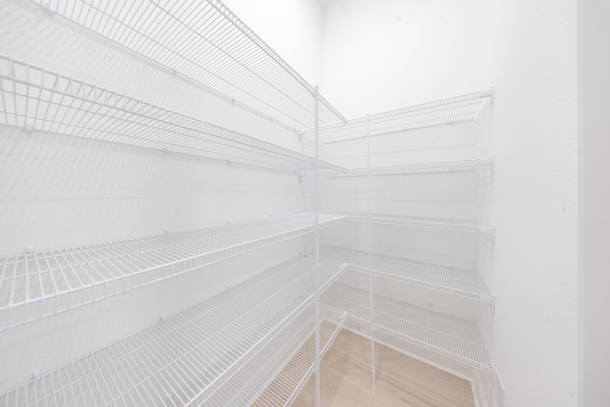 Walk-in pantry with floor-to-ceiling wire shelving on two walls