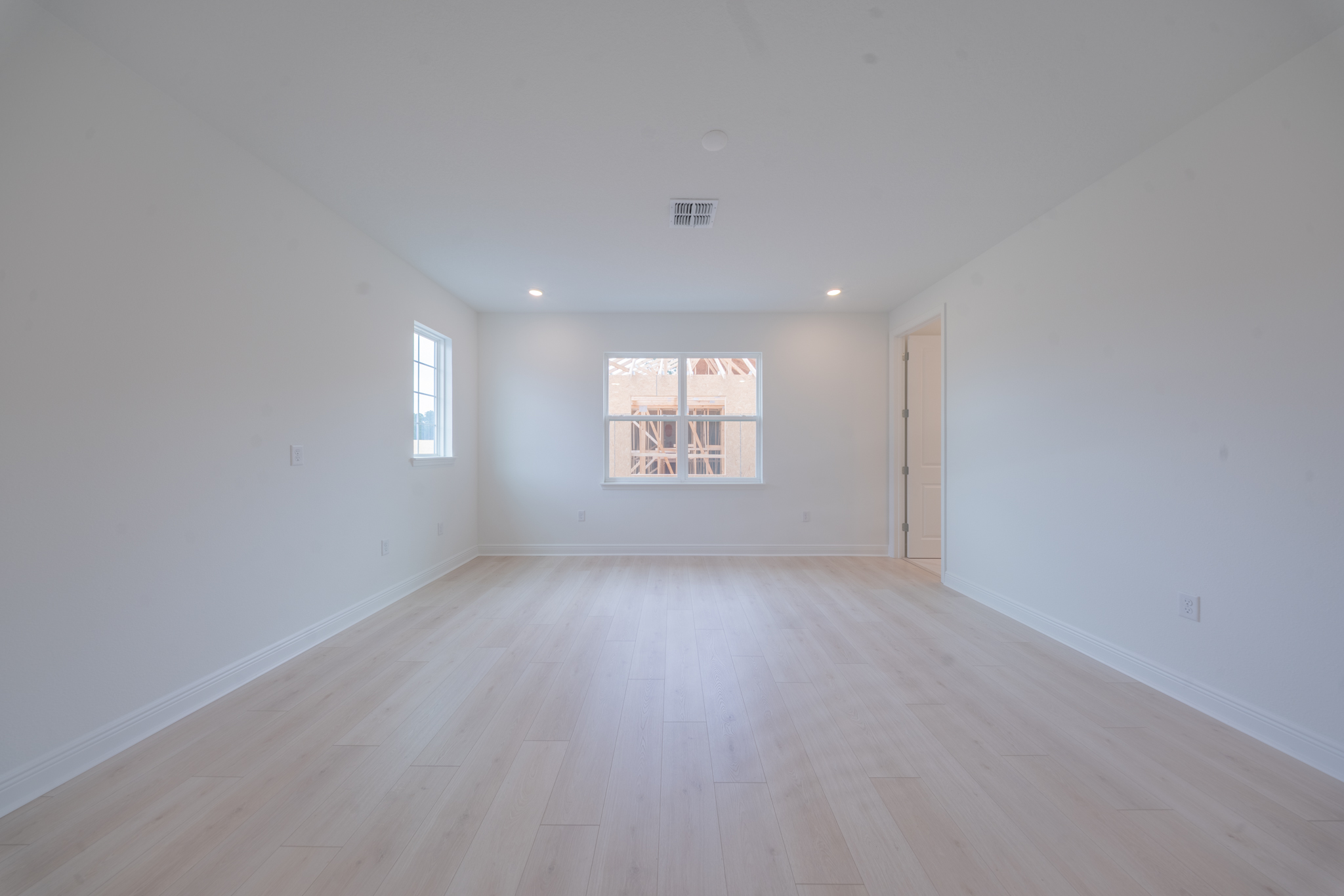 Empty bonus room with light hardwood floors and two windows