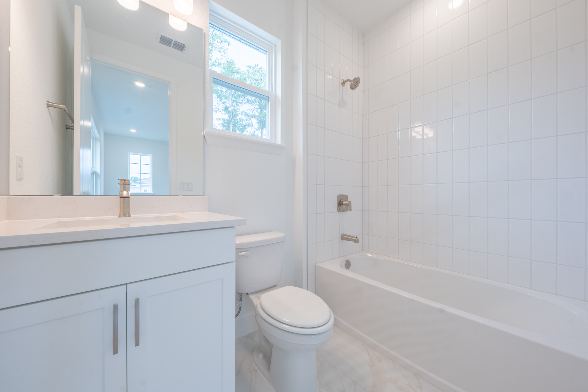 Bathroom with single vanity, large mirror and tub/shower combo with white tile