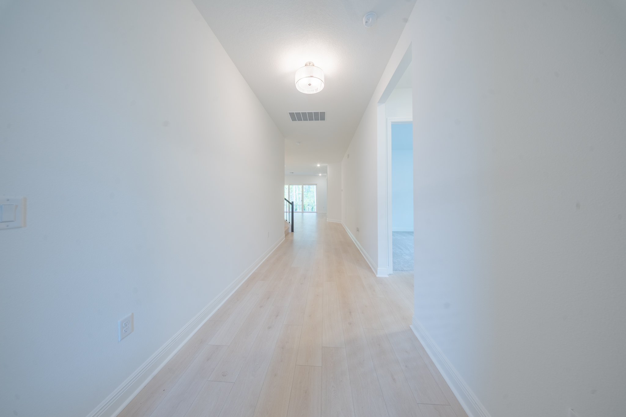 Entry hallway with flush-mount light leading toward open-plan living area