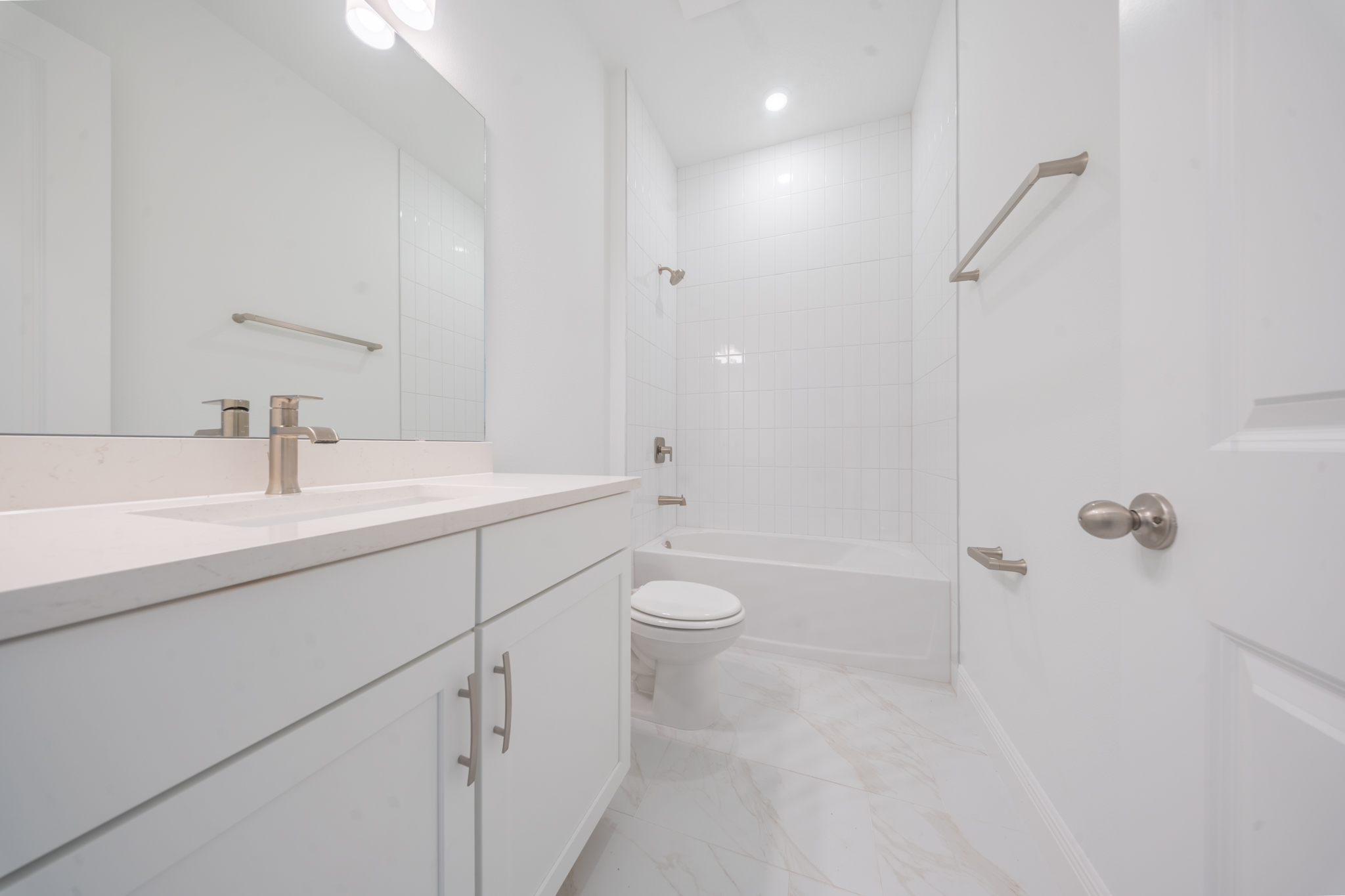 Bathroom with single vanity, large mirror and tub/shower combo with white tile