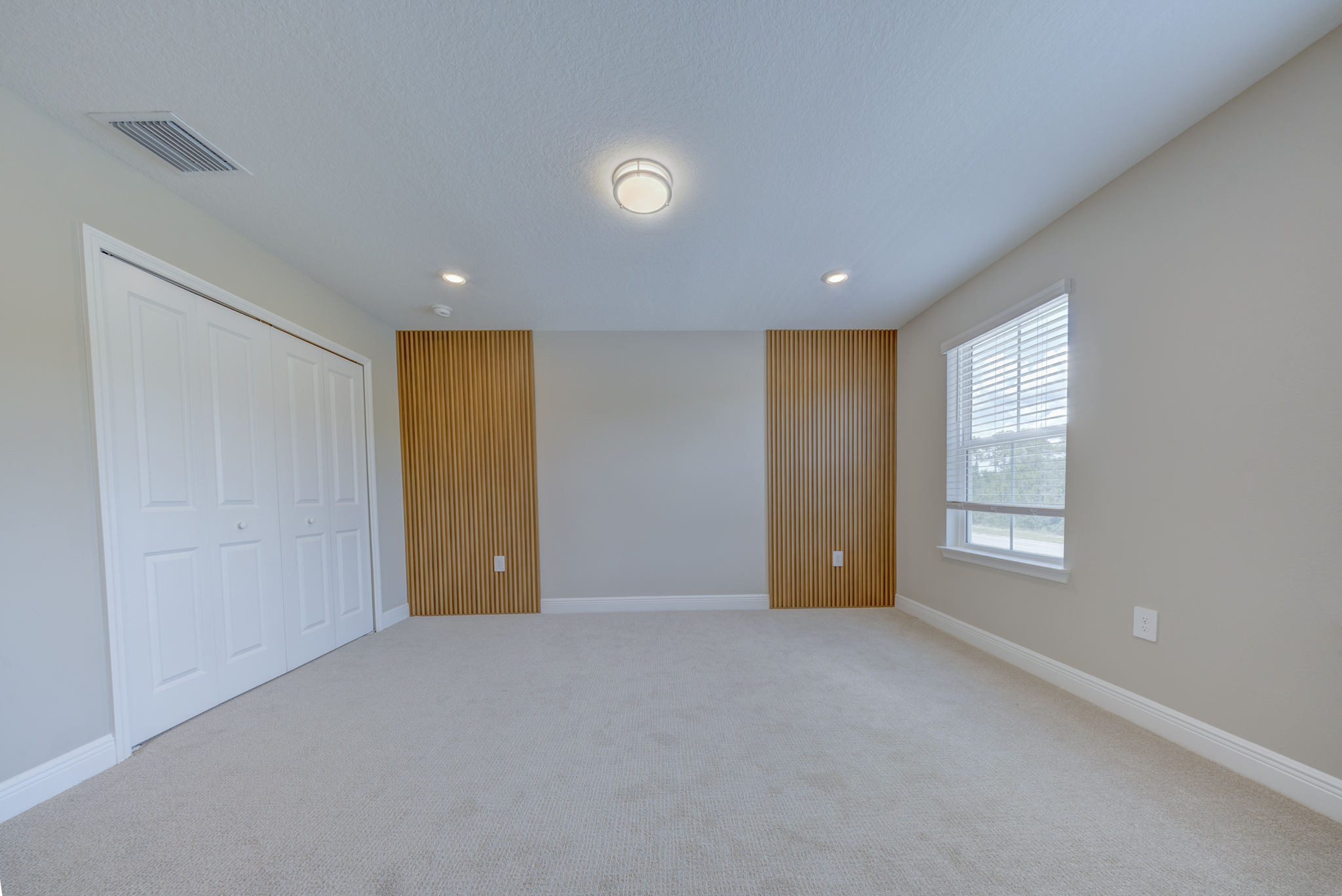 Empty bedroom with two vertical wood slat accent columns, double-door closet and single window