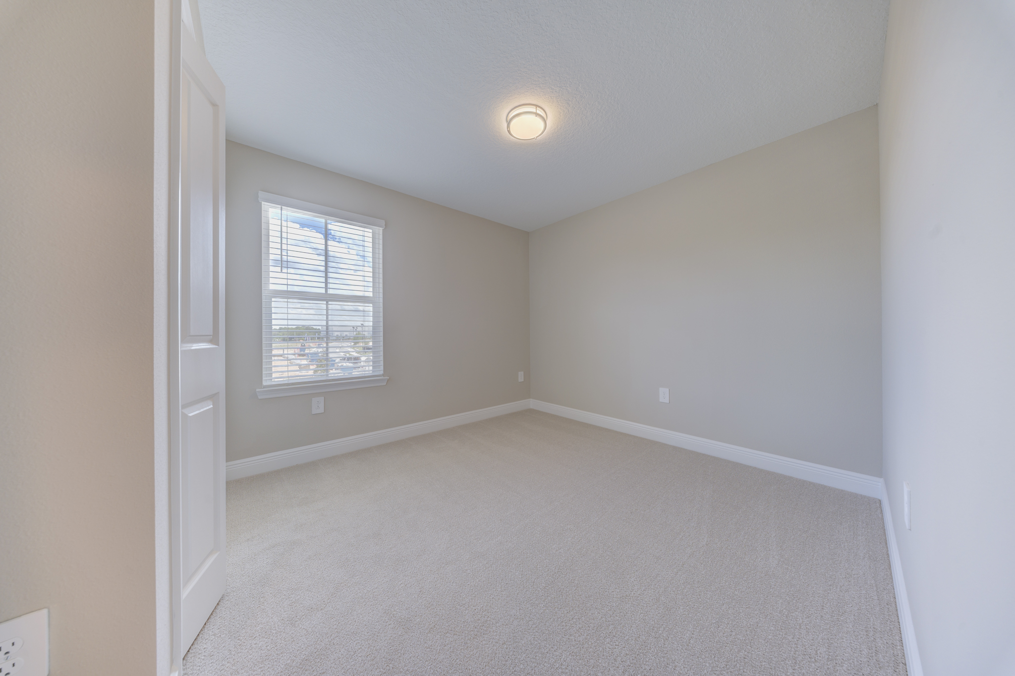Small empty carpeted bedroom with single window