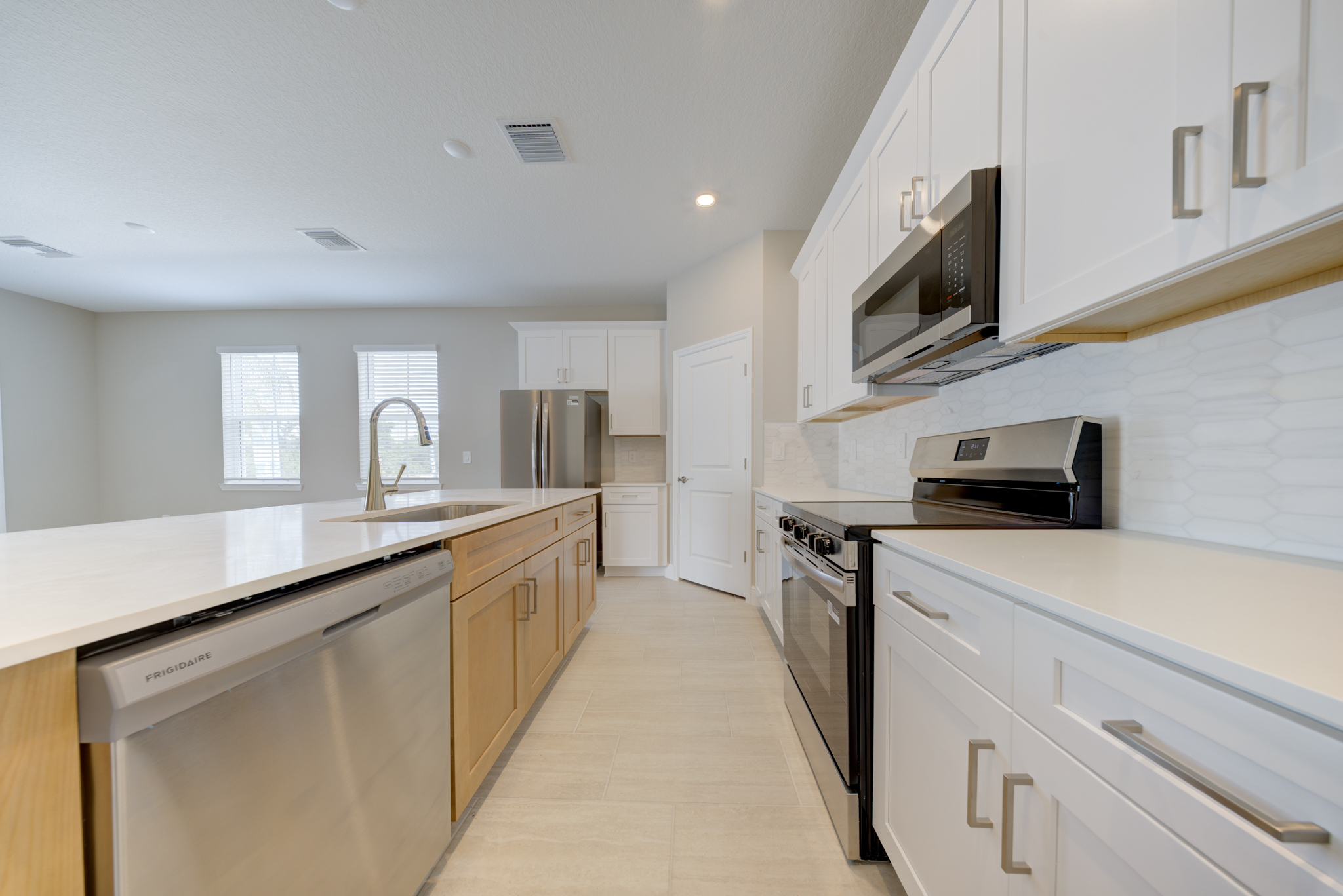 Kitchen with white upper shaker cabinets, natural wood island, quartz countertops and stainless appliances
