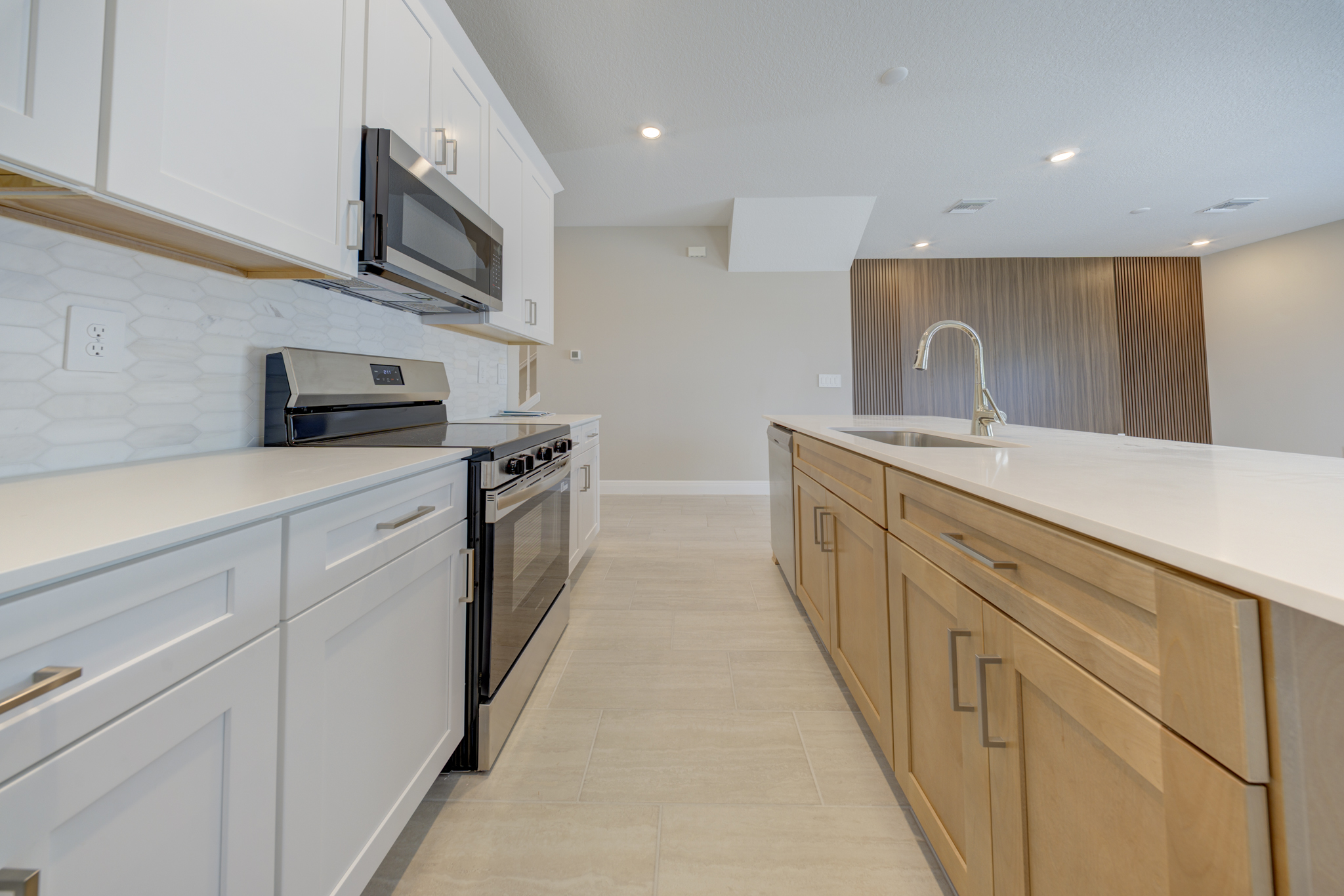 Kitchen detail with natural wood island, stainless range and hexagon backsplash looking toward wood slat accent wall