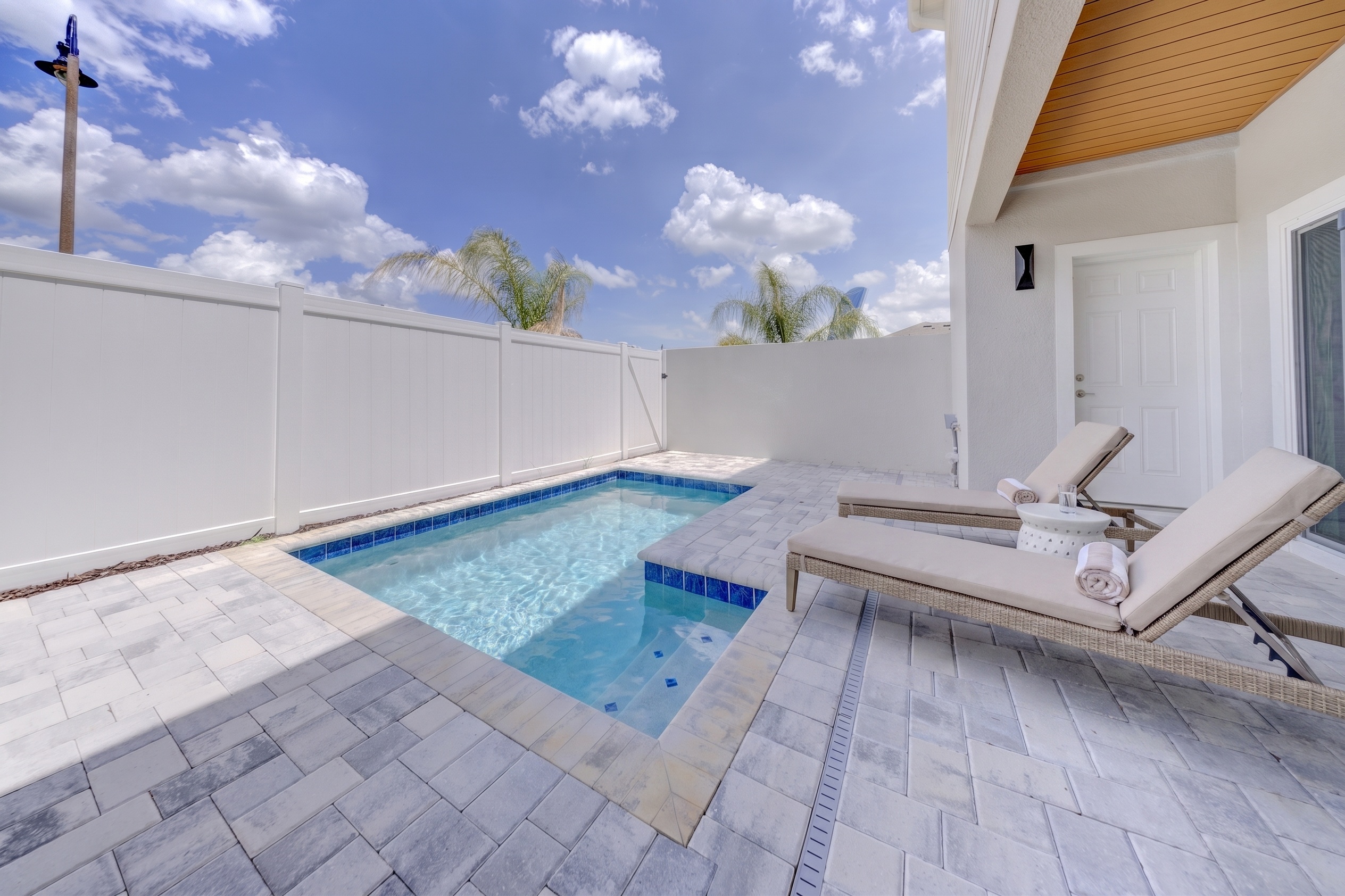 Private plunge pool with paver deck, lounge chairs and two-story home exterior