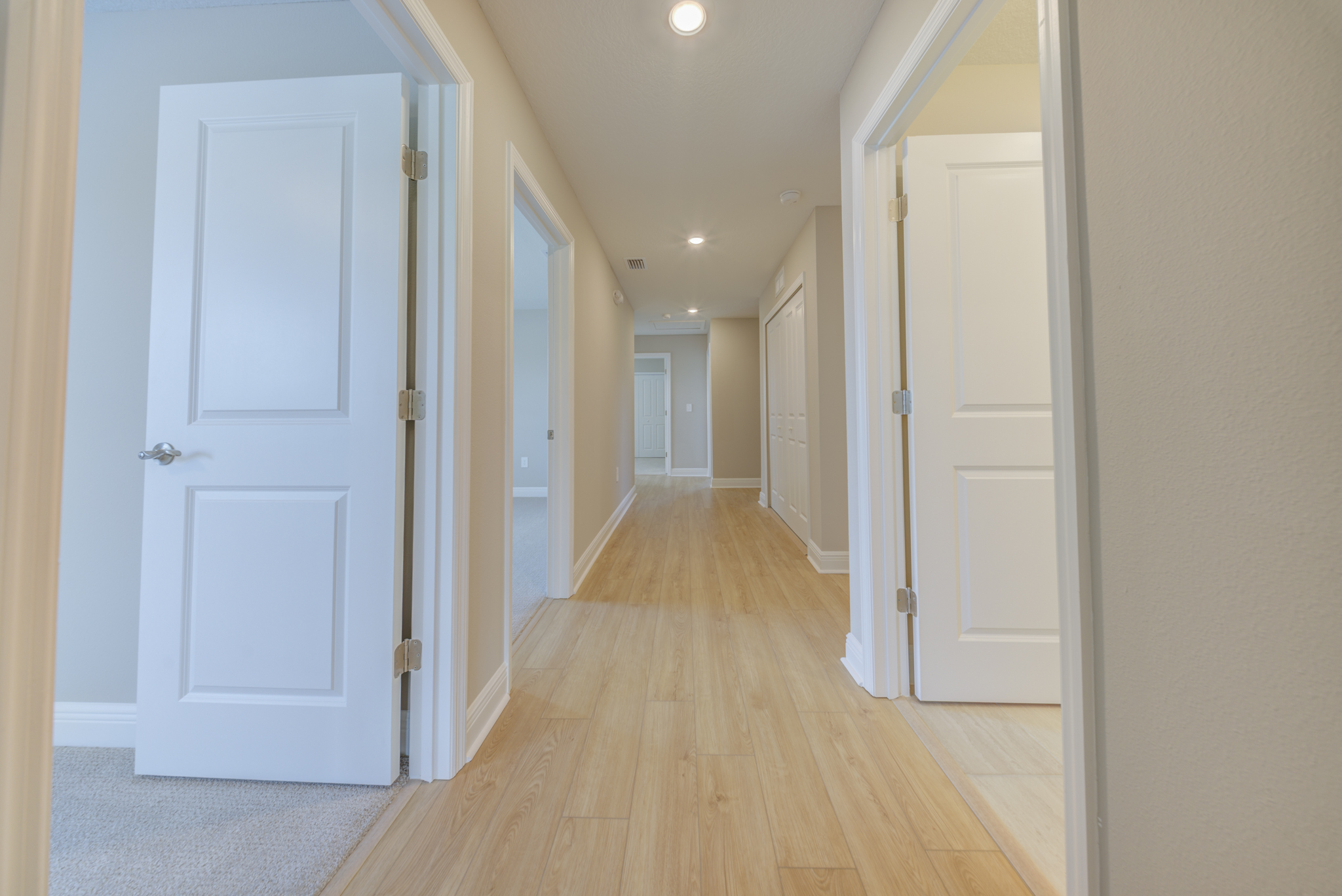Upper floor hallway with light hardwood floors and multiple bedroom doors