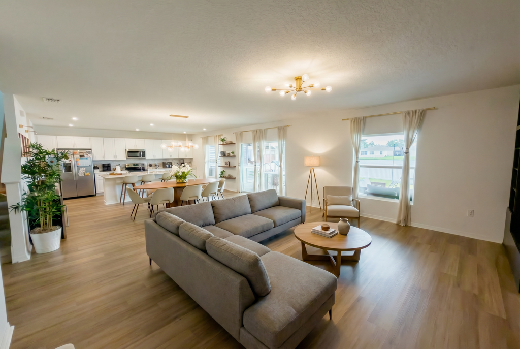 Living room with gray sectional sofa, round coffee table and open kitchen in background