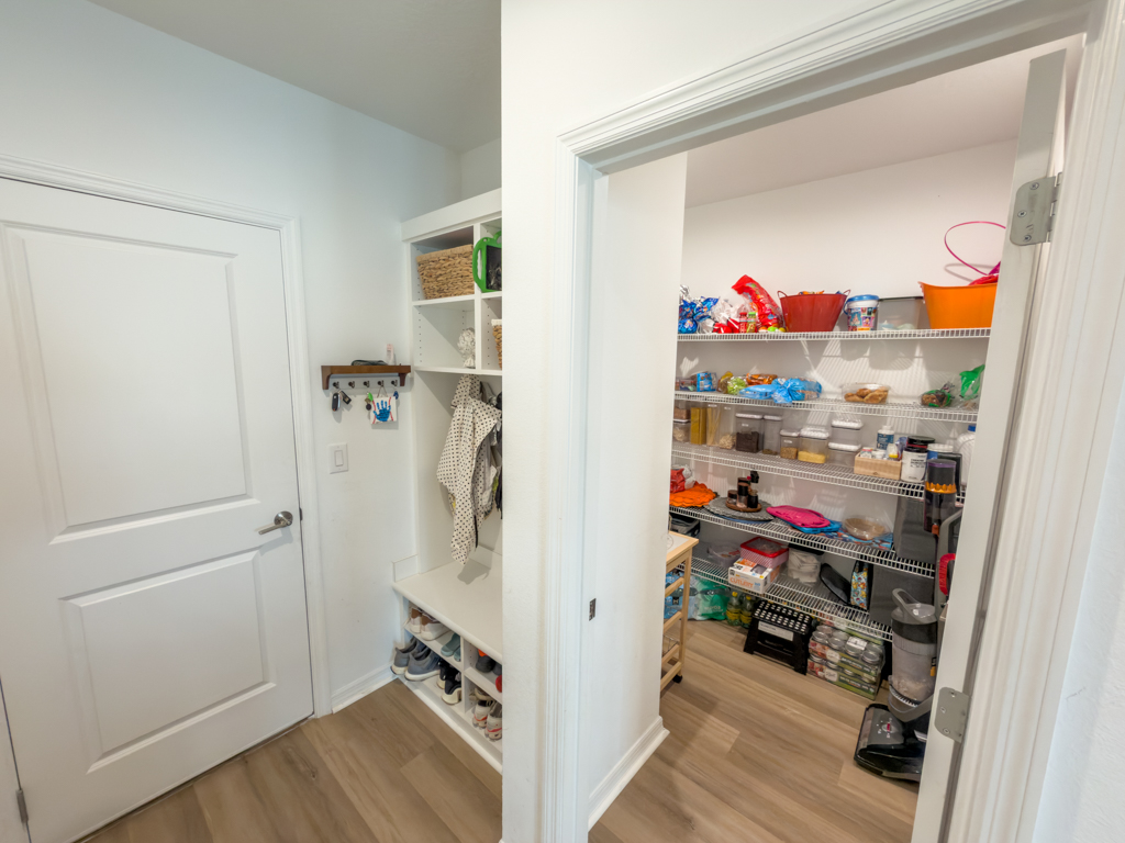 Mudroom with built-in bench and cubbies beside walk-in pantry entrance