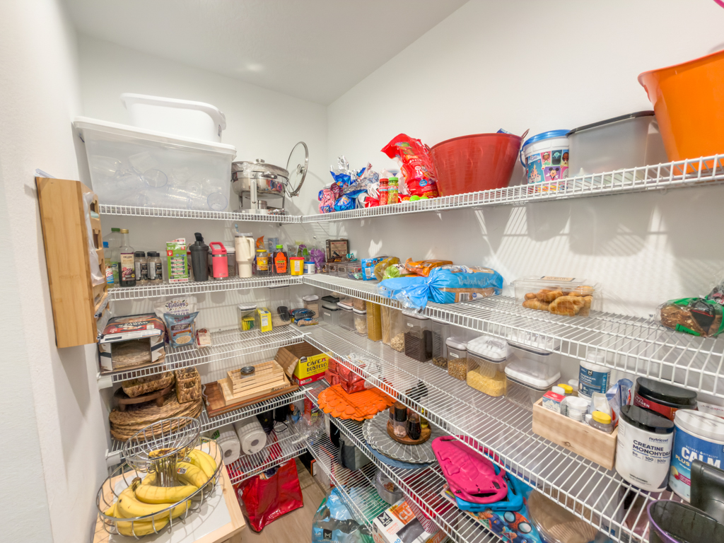 Walk-in pantry with wire shelving stocked with food and supplies