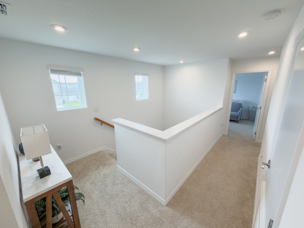 Upstairs hallway landing with carpeted floor and multiple bedroom doors