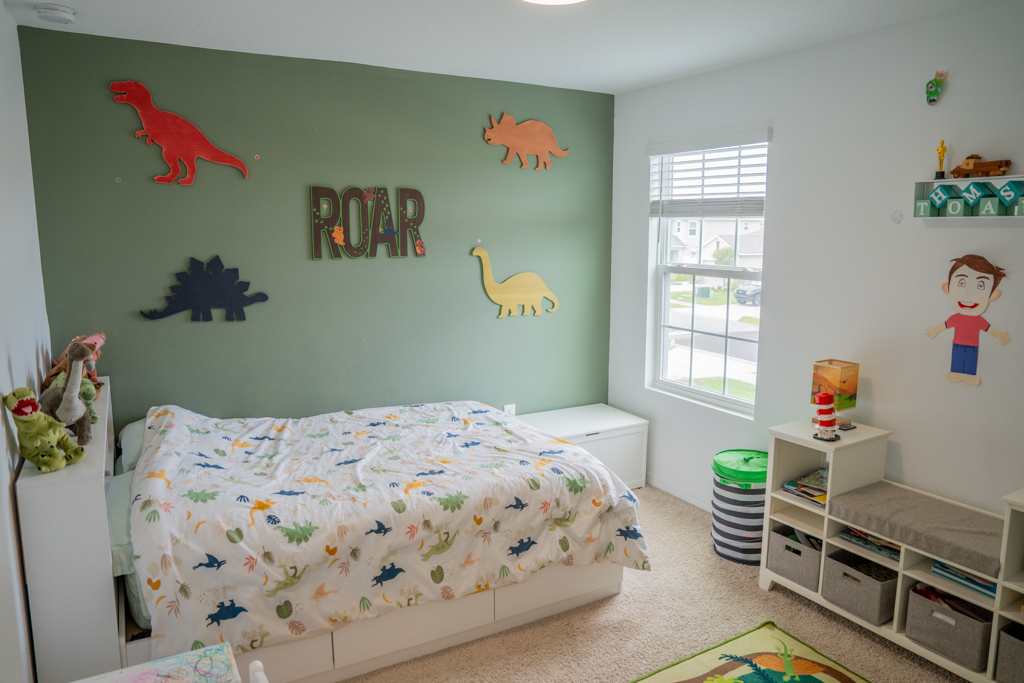 Boy's bedroom with dinosaur décor and green accent wall