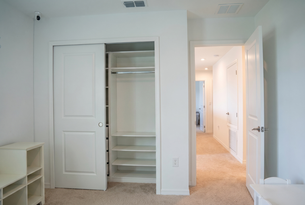 Virtually staged empty bedroom closet with shelving and hallway view
