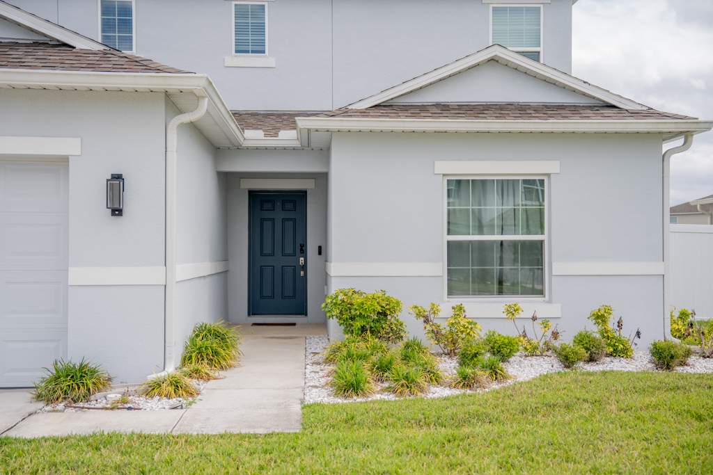 Close-up of front entry door with stone-accented landscaping