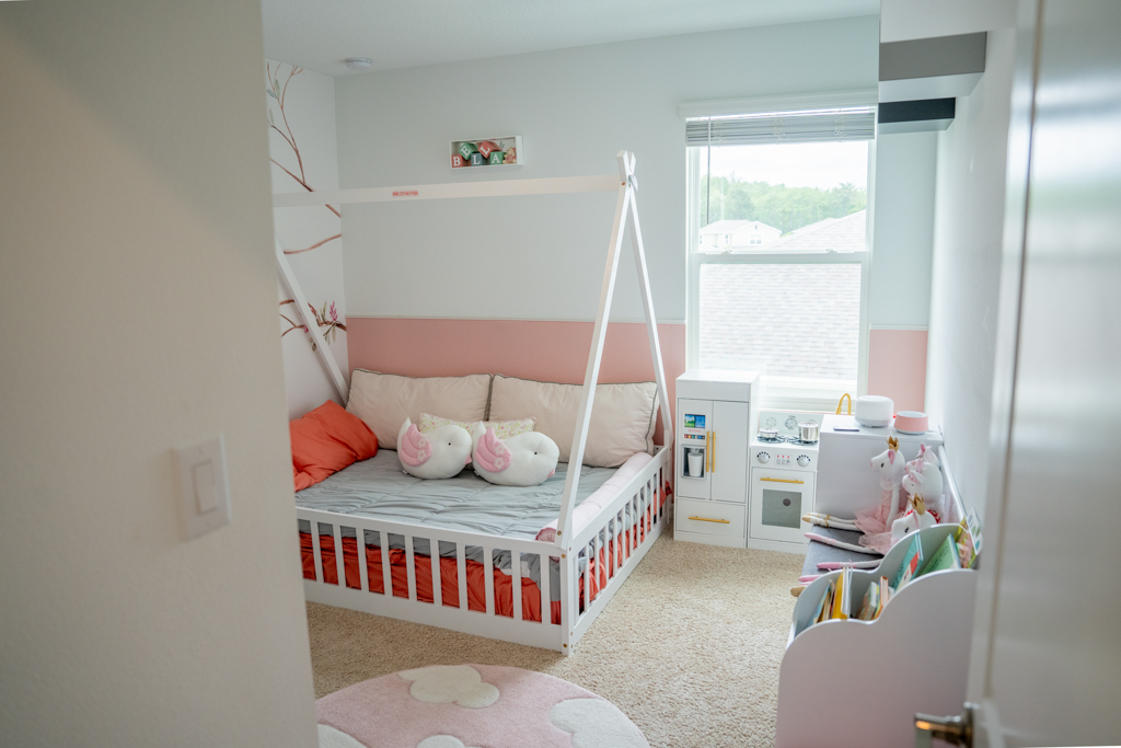 Toddler girl's bedroom with teepee bed frame, pink accents and play kitchen