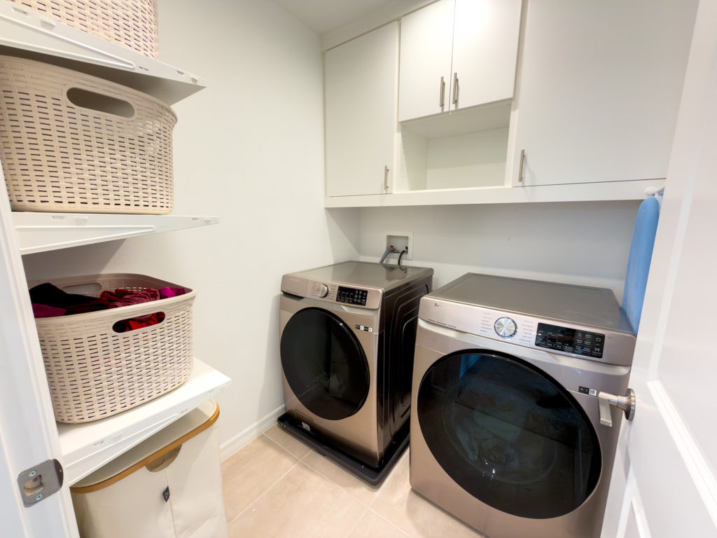 Laundry room with front-load washer and dryer, upper cabinets and shelving